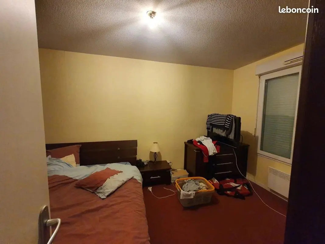 Chambre avec lit, mobilier et affaires du précédent occupant.