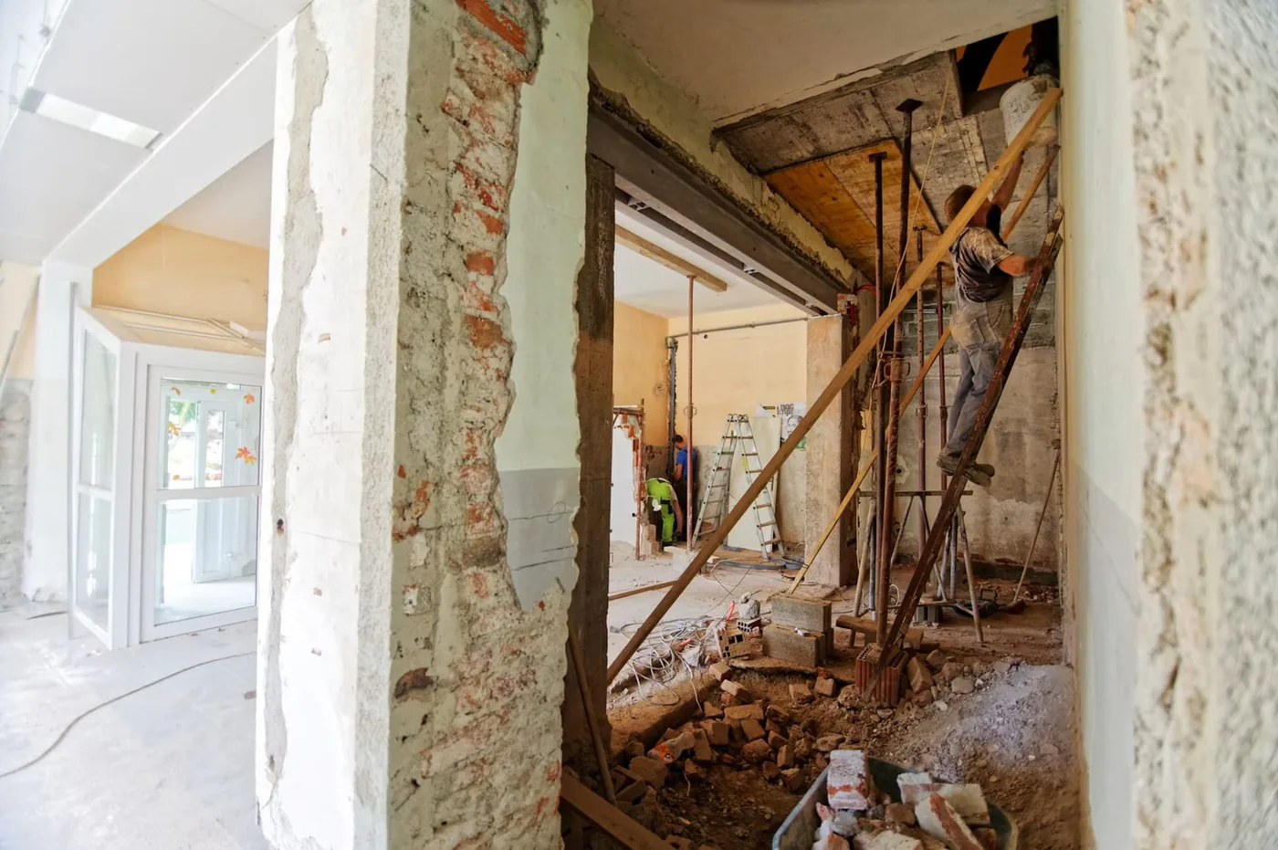 Ouverture d'un mur porteur sur un chantier de rénovation, linteau posé et gravats au sol.