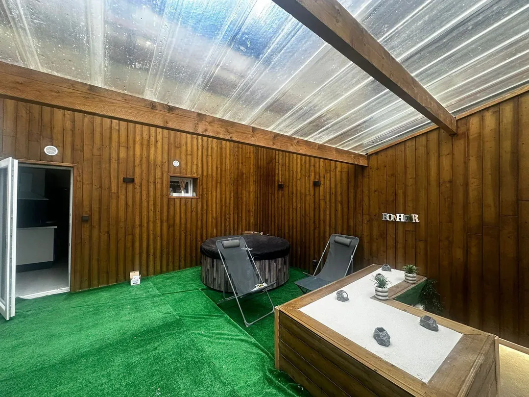 La cour aménagée : bardage bois, gazon synthétique, spa gonflable et bacs de jardinage.