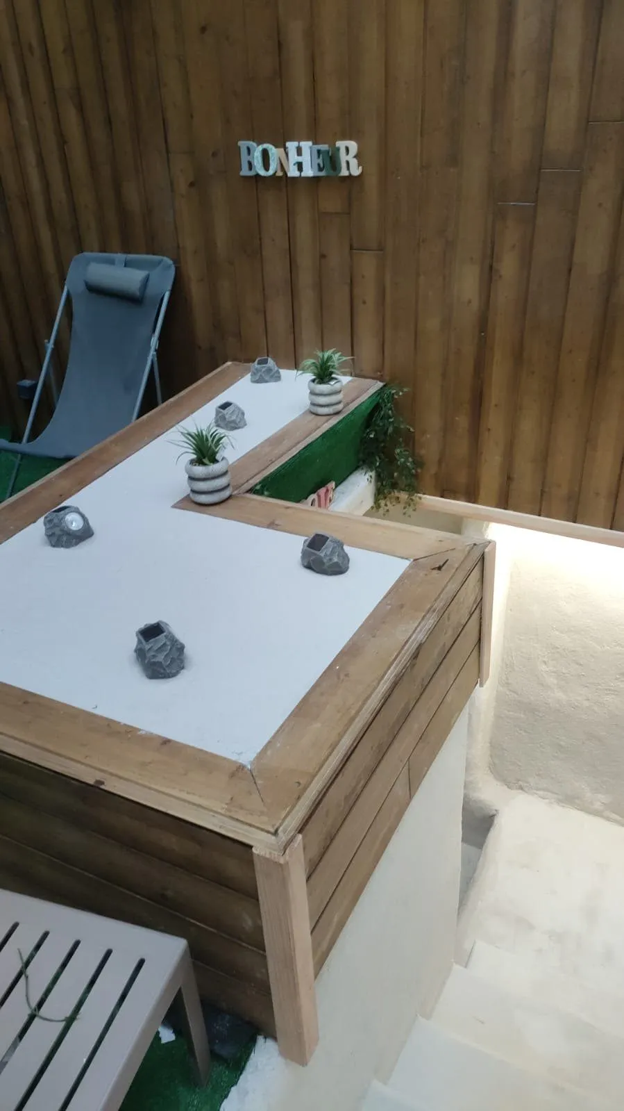 Autre angle de la cour aménagée, avec transats et jardinières surélevées.