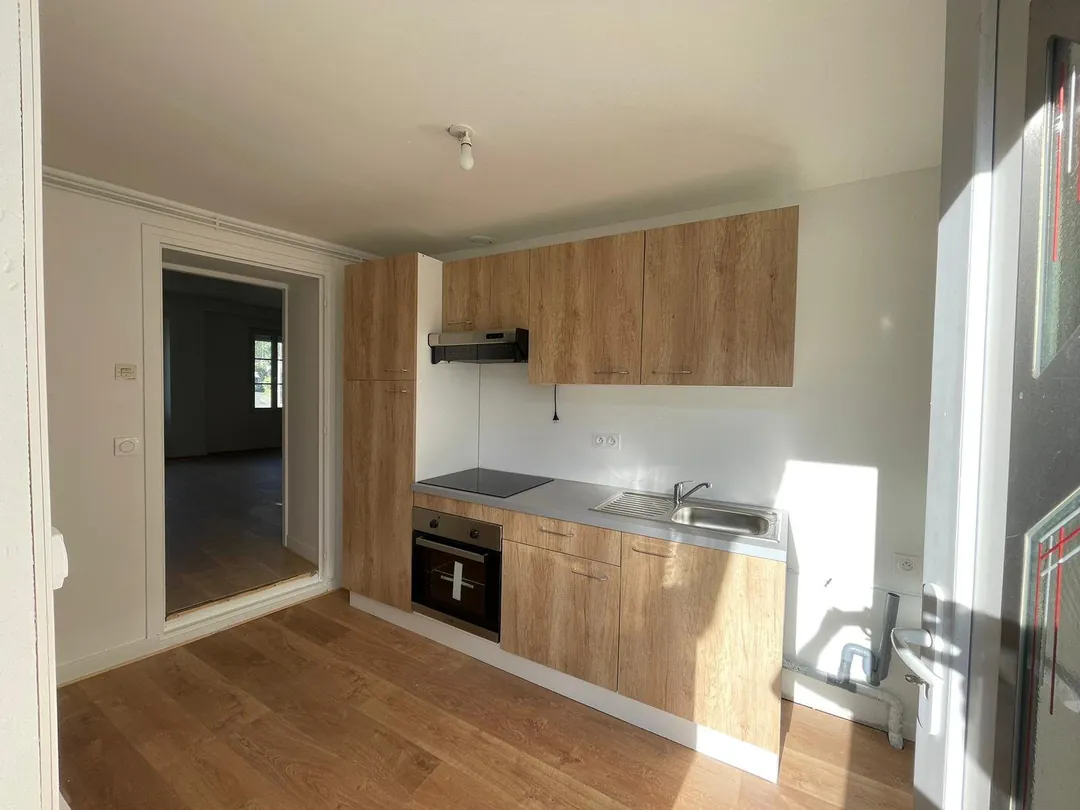 Cuisine refaite : meubles bois, plan de travail et fenêtre au fond.