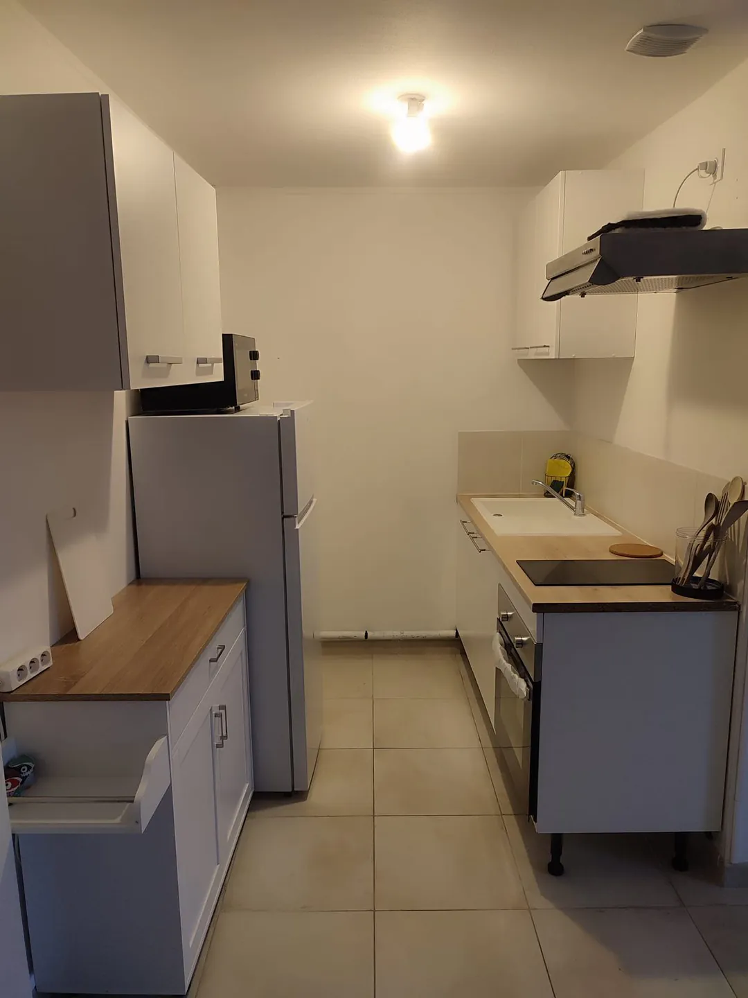 La cuisine vue de biais, avec micro-ondes et réfrigérateur.