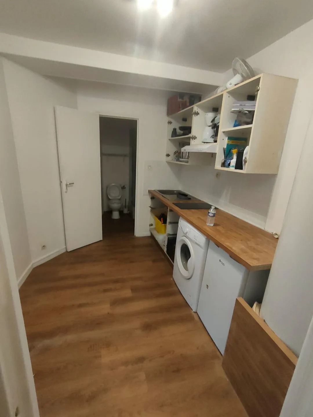 Cuisine refaite : plaque de cuisson, plan de travail bois et rangements ouverts.