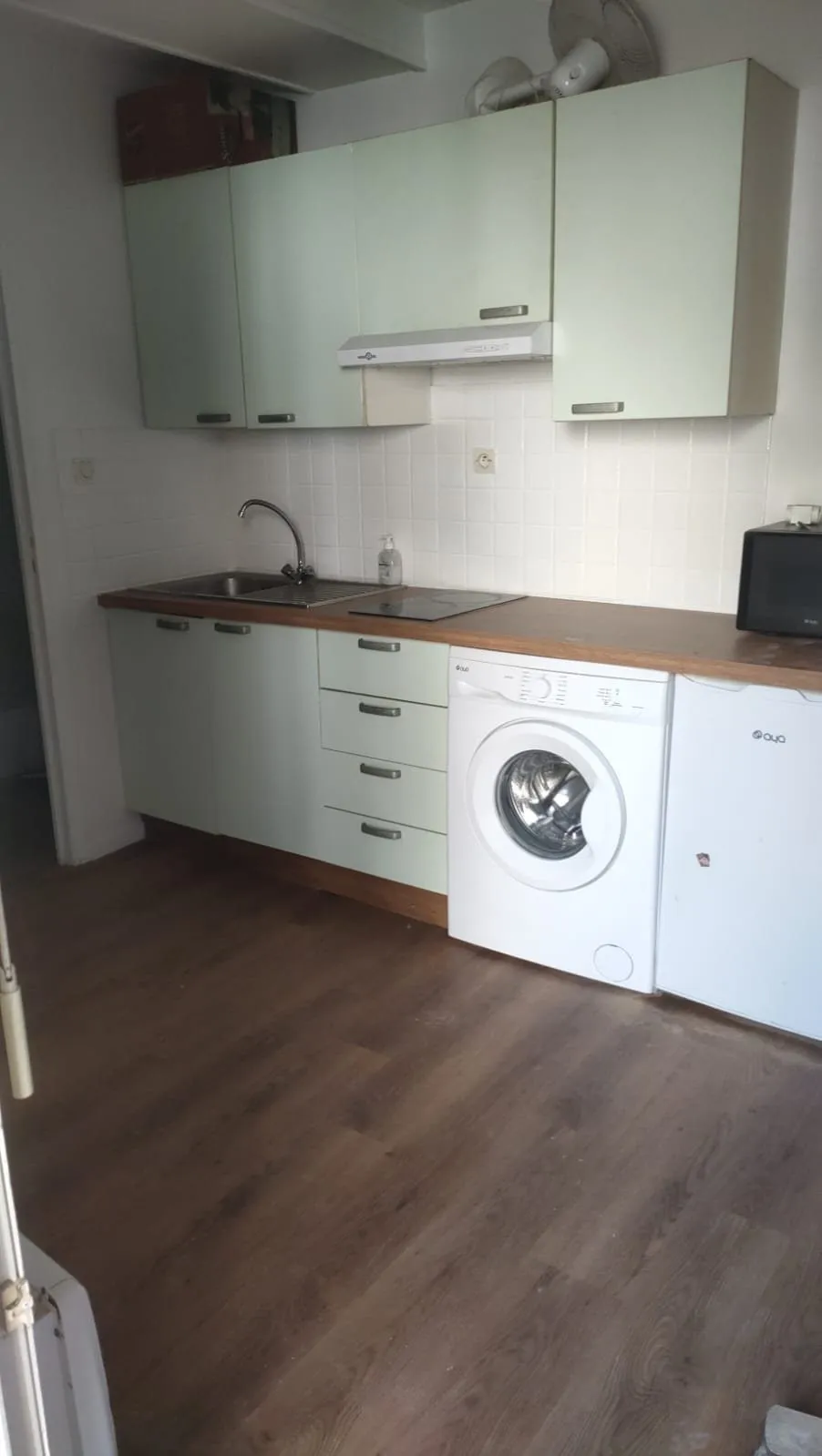 Cuisine équipée en fin d'aménagement : évier, plan de travail bois, lave-linge et lave-vaisselle.