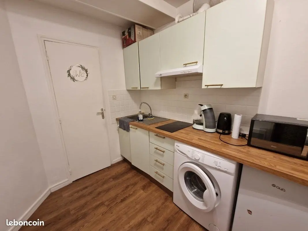Cuisine refaite : plan de travail bois, façades claires, lave-linge intégré.