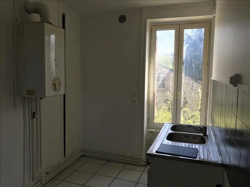 Cuisine vue depuis la porte, évier ancien et fenêtre au fond.