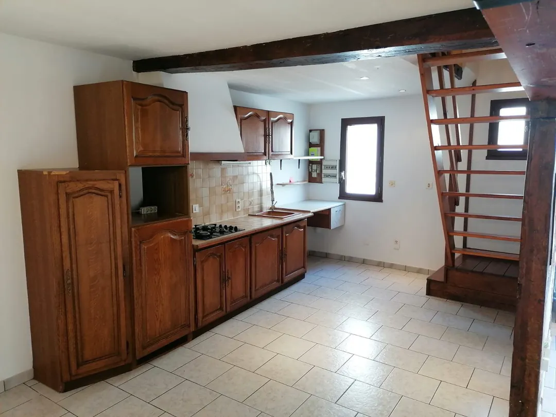 La cuisine en chêne vue depuis le séjour, escalier au fond.