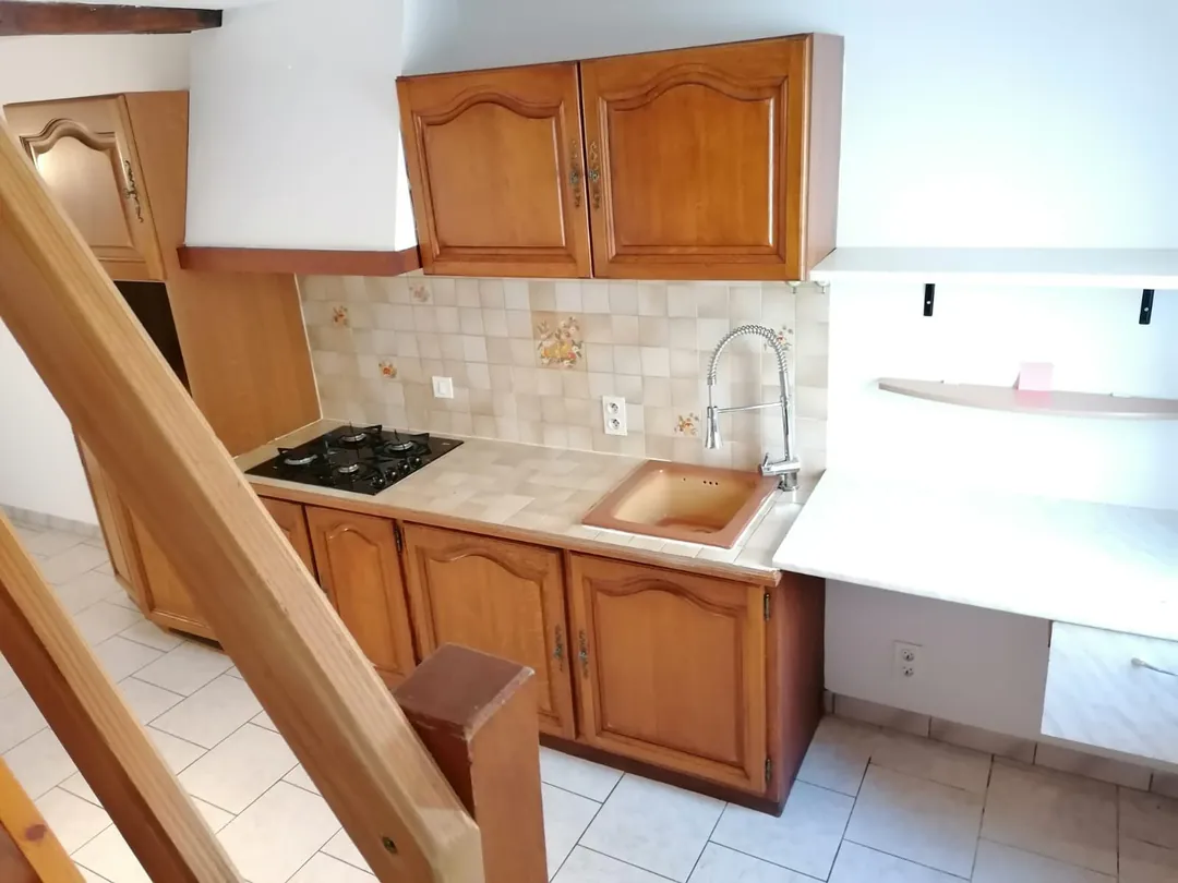 Plan de travail d'origine : évier, plaque de cuisson et rangements hauts en bois.