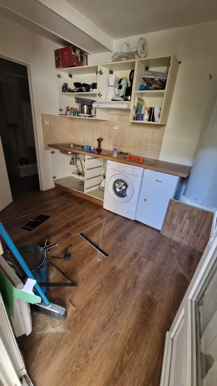 La cuisine en fin de chantier : sol refait, plan de travail bois, barre à outils encore au sol.