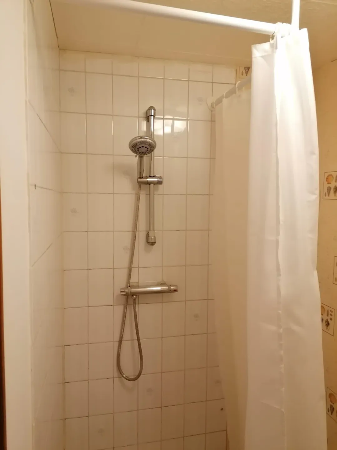 Douche d'origine carrelée, colonne et rideau.