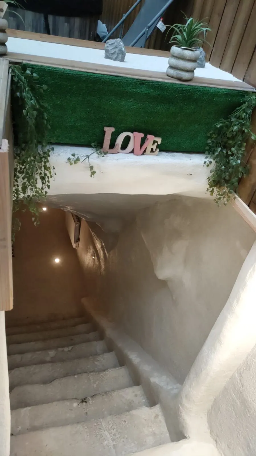 Le même escalier terminé : enduit blanc, éclairage encastré, décoration végétale en haut des marches.