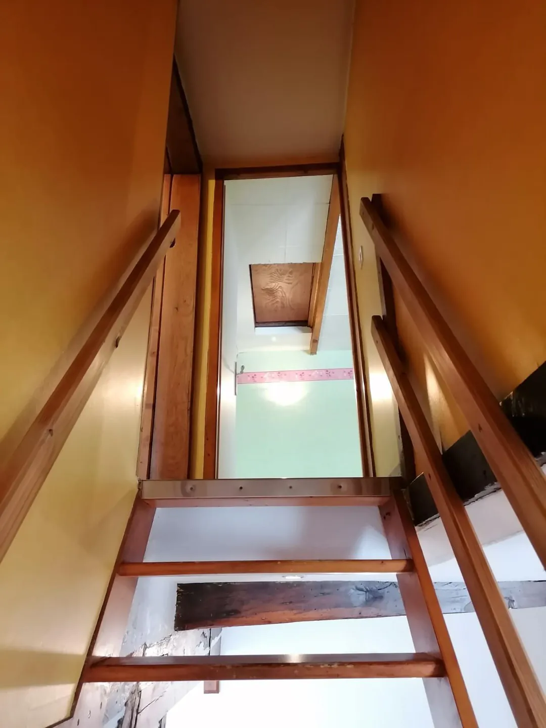 Vue plongeante depuis le haut de l'escalier vers le rez-de-chaussée.
