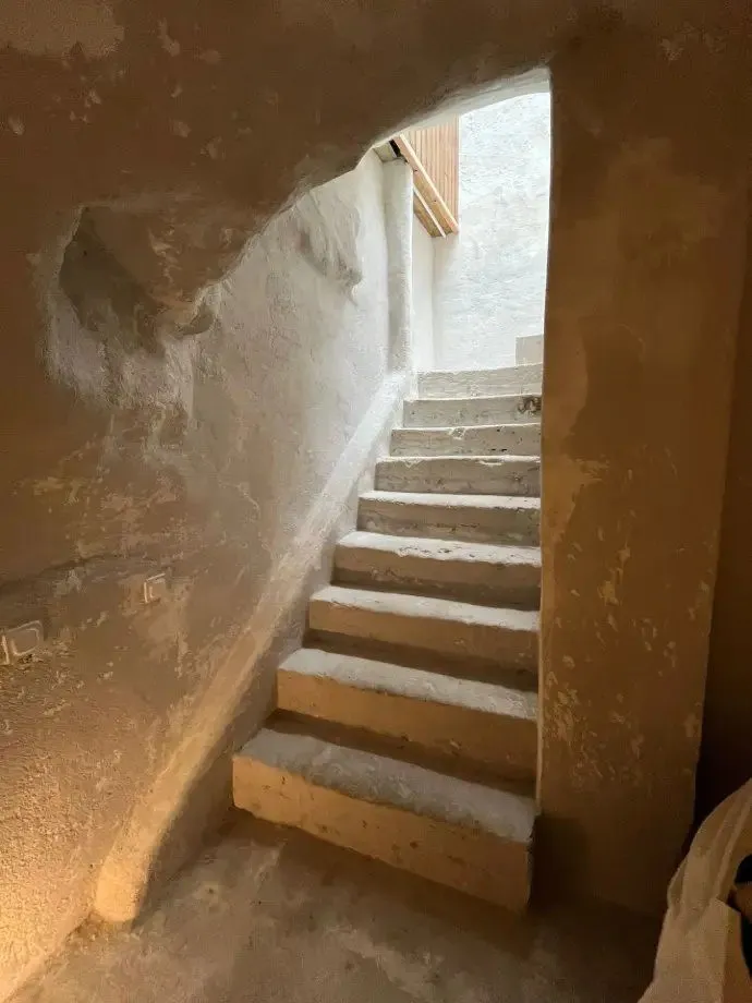 Escalier en béton brut pendant les travaux, murs décapés jusqu'à la pierre.