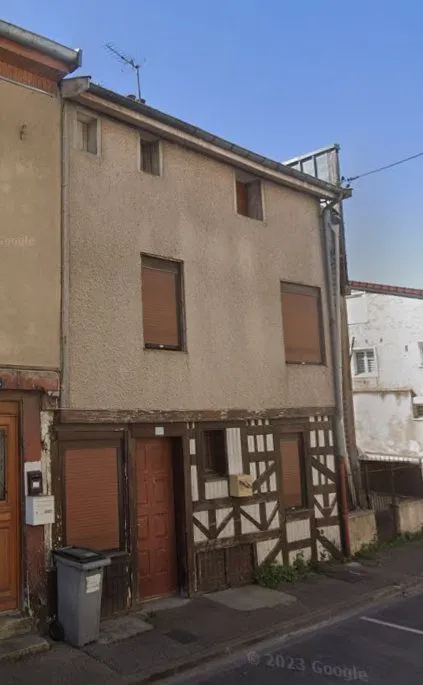 La maison vue depuis l'autre côté de la rue, pignon enduit et colombages en façade.