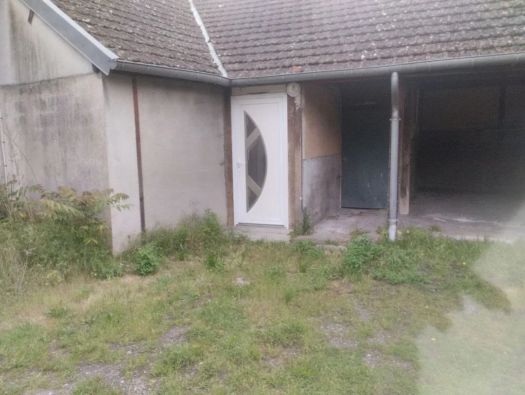 Dépendances en enfilade, ouvertures maçonnées et sol herbeux.
