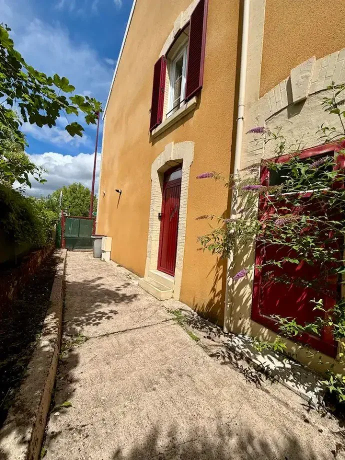 Façade ocre d'un immeuble ancien longé par un chemin bordé de végétation.