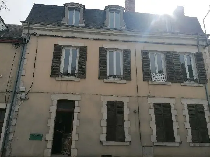 Immeuble ancien de deux étages avec toiture en ardoise, vu depuis la rue.