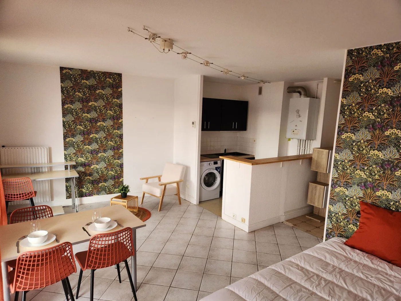 Studio meublé avec lit, coin repas et cuisine ouverte.