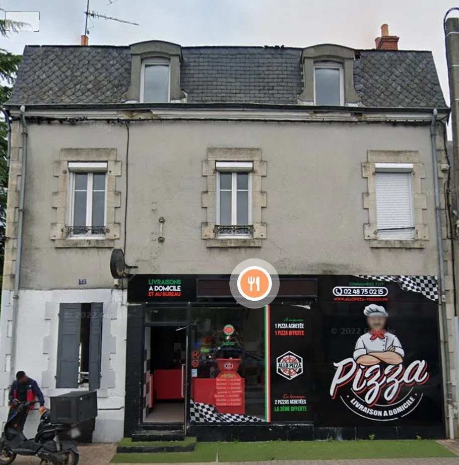 Immeuble de deux étages avec un commerce en rez-de-chaussée.