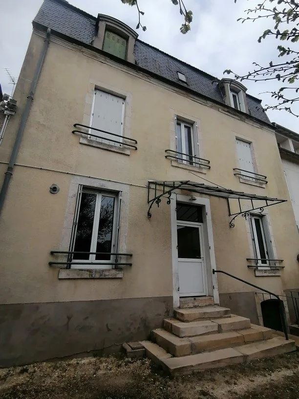 Immeuble ancien en pierre avec perron et fenêtres à volets.