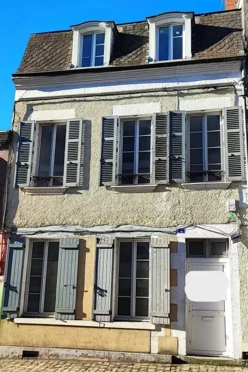 Maison de ville en pierre à trois niveaux avec lucarnes et volets bleus.