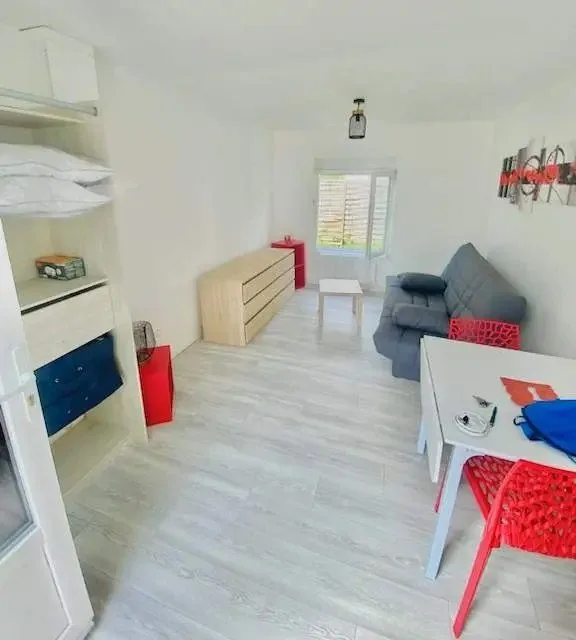 Pièce de vie meublée avec lits superposés, bureau et canapé.