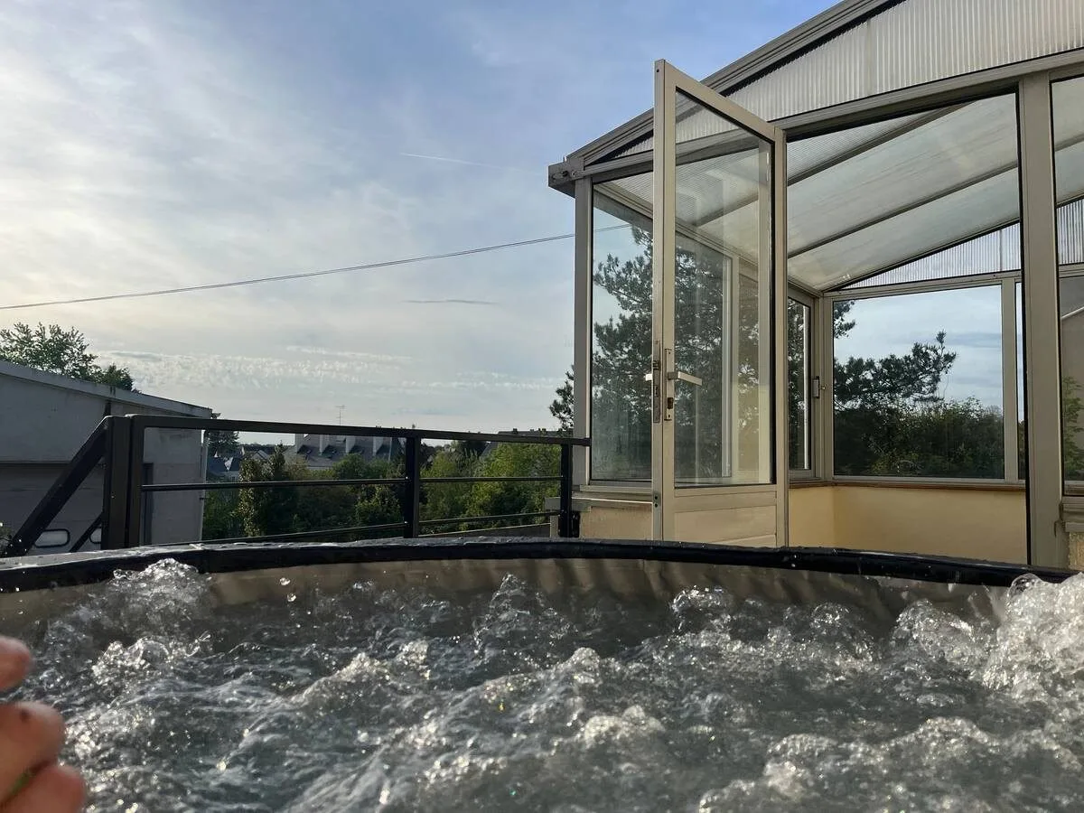 Véranda vitrée abritant un spa en eau, vue sur le jardin.