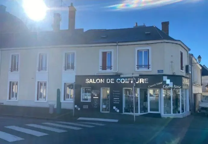 Immeuble d'angle avec un salon de coiffure en rez-de-chaussée.