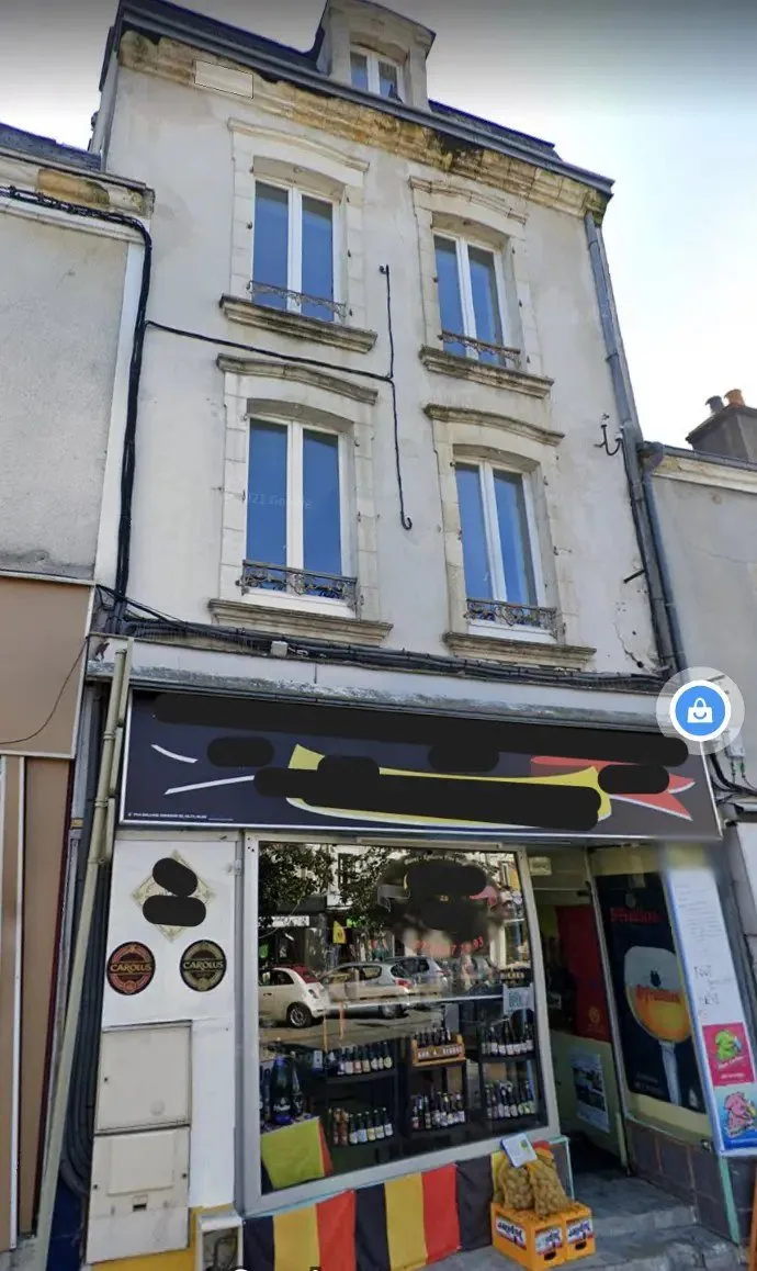 Immeuble ancien de trois niveaux avec un commerce en rez-de-chaussée.
