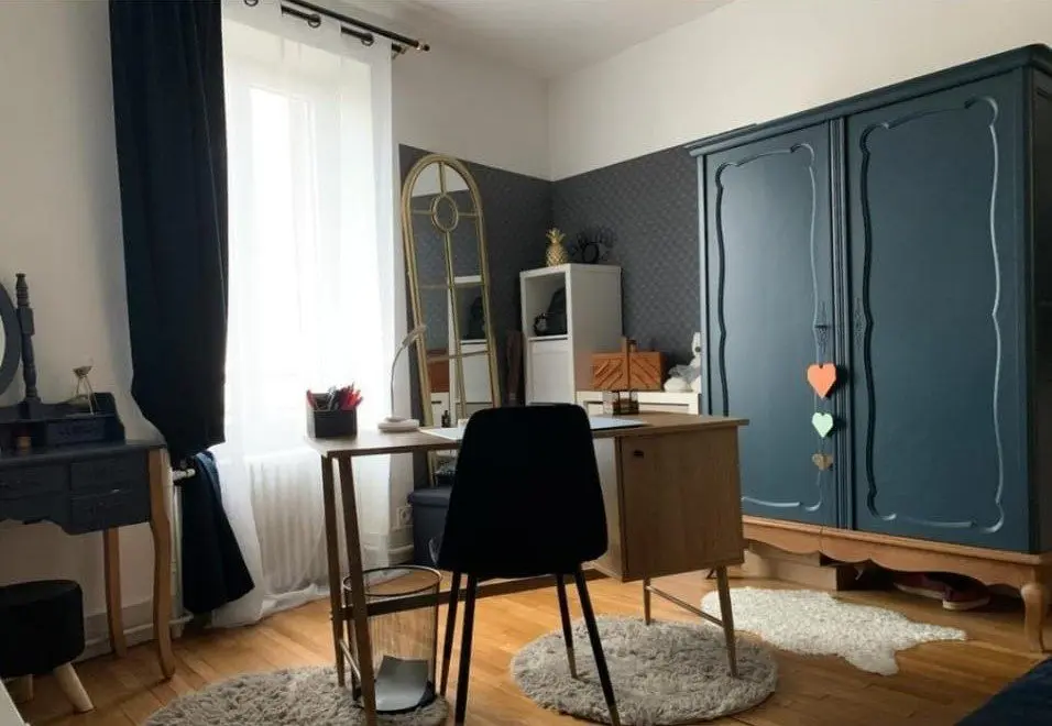 Salle à manger avec table, chaises et grande armoire bleue.