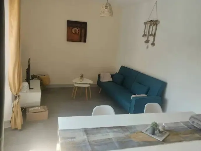 Pièce de vie avec canapé bleu, table basse et rideau jaune.