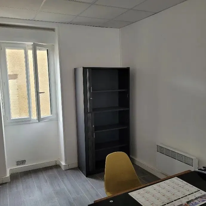 Local professionnel avec étagère noire, chaise et fenêtre.