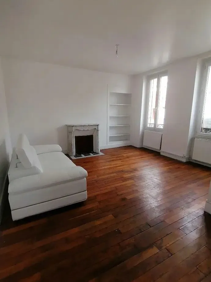 Salon au parquet ancien avec cheminée en marbre et niches de rangement.