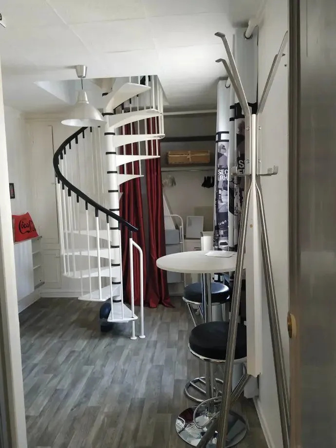 Escalier en colimaçon blanc à côté d'une table ronde et de tabourets.