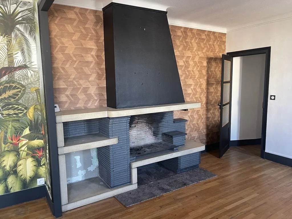 Cheminée habillée de noir avec niches de rangement, papier peint à motifs.