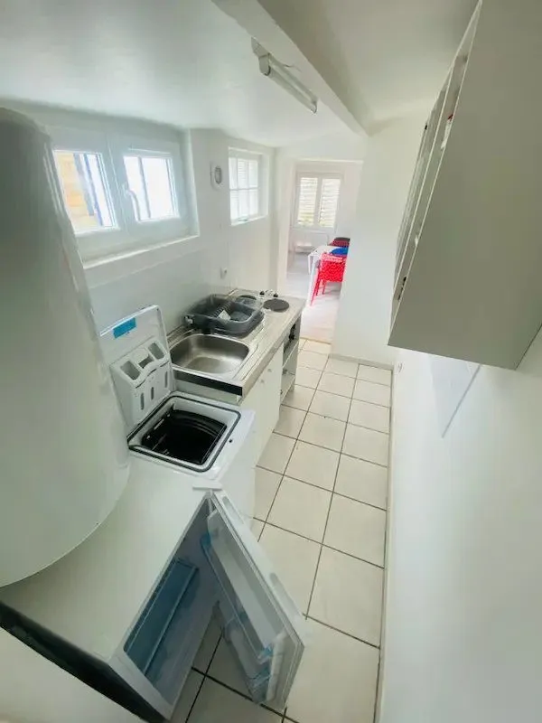 Cuisine étroite avec plaque, four, évier et rangements blancs.