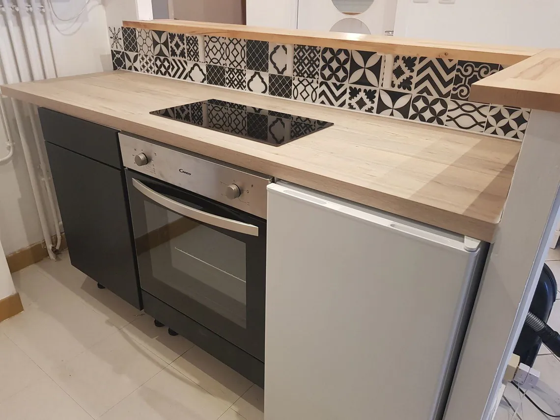 Cuisine avec plan de travail bois, plaque à induction et crédence à motifs.
