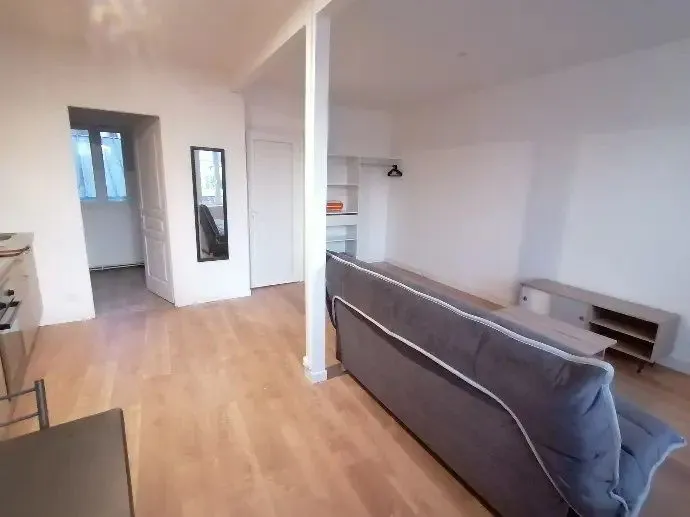 Séjour avec canapé, poteau porteur et parquet clair.