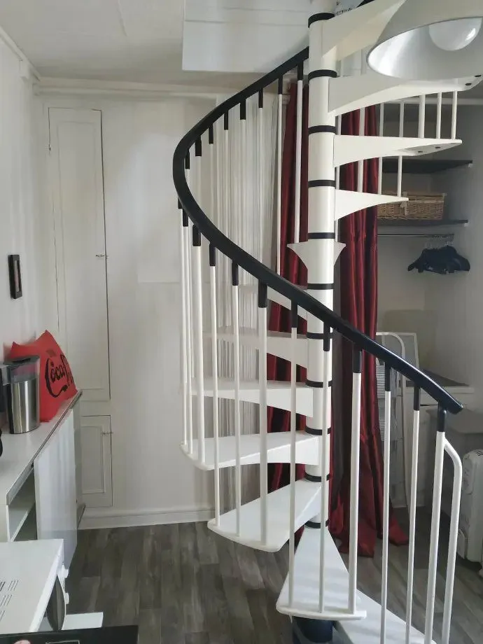 Escalier en colimaçon blanc à rampe noire, vu depuis le bas.