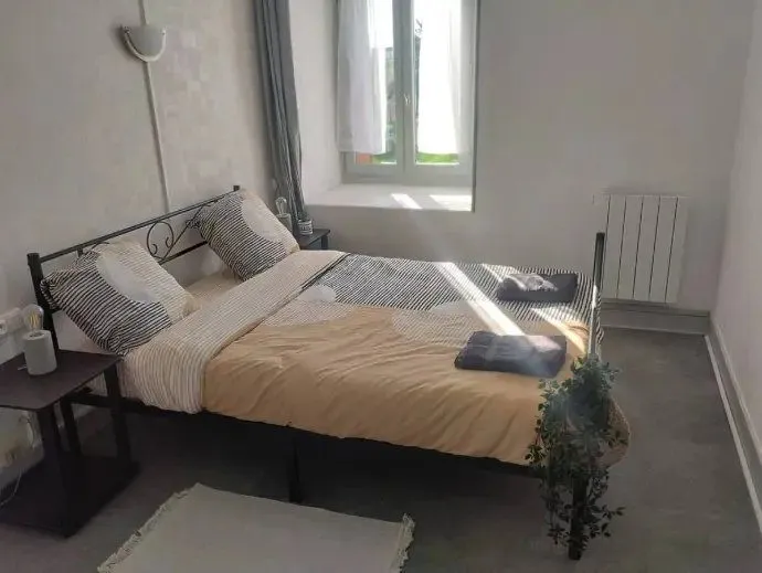 Chambre avec lit double, couvre-lit ocre et fenêtres.