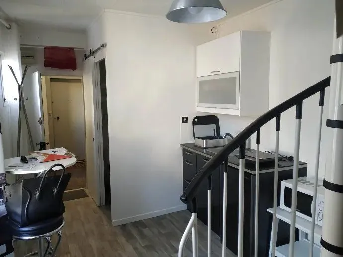 Kitchenette avec rangements hauts, micro-ondes et escalier au fond.