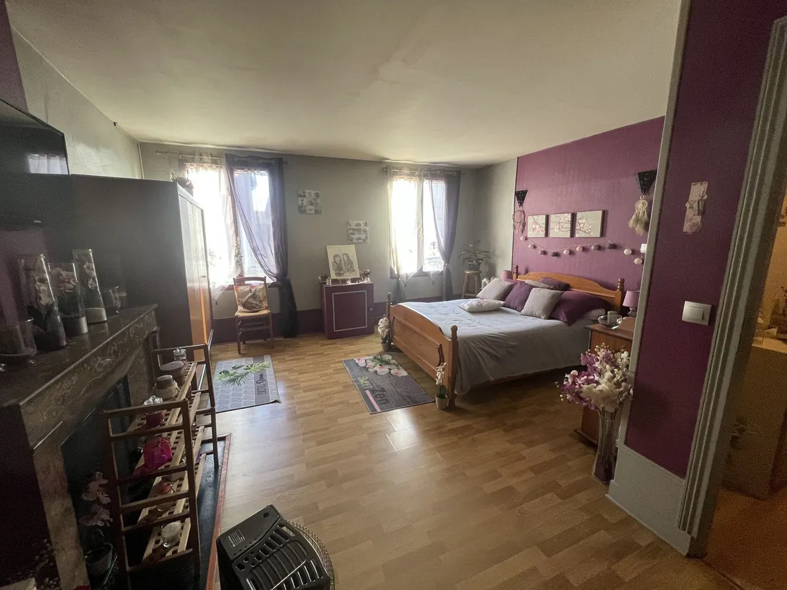 Chambre occupée avec lit double, mur prune et rangements.