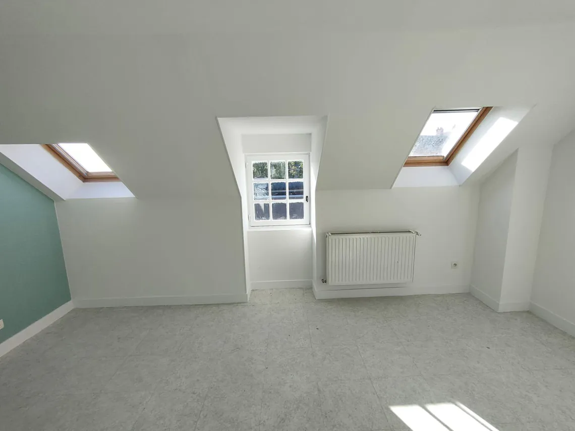 Chambre sous rampant avec deux fenêtres de toit et murs vert d'eau.