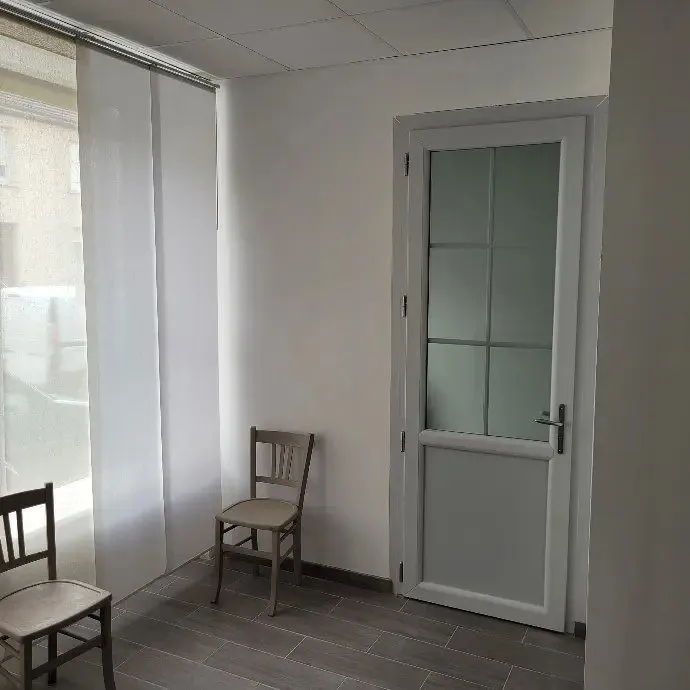 Pièce claire avec porte vitrée, chaise et panneaux coulissants.