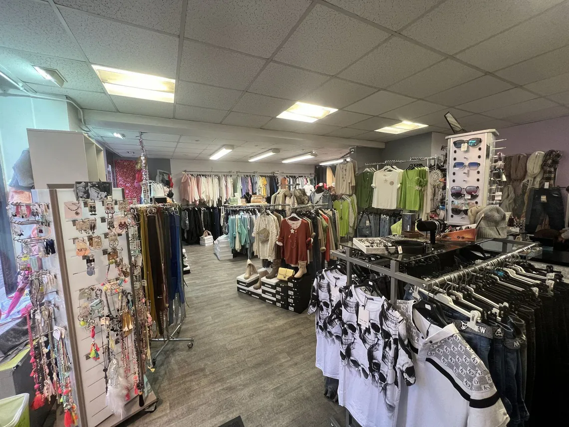 Boutique de vêtements avec portants, présentoirs et faux plafond.