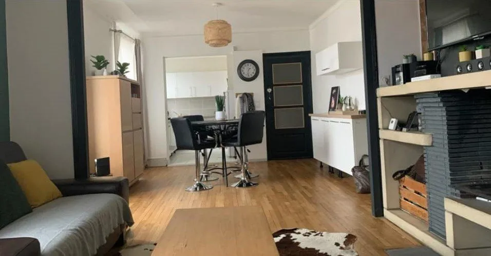 Séjour avec canapé, coin repas et parquet clair.