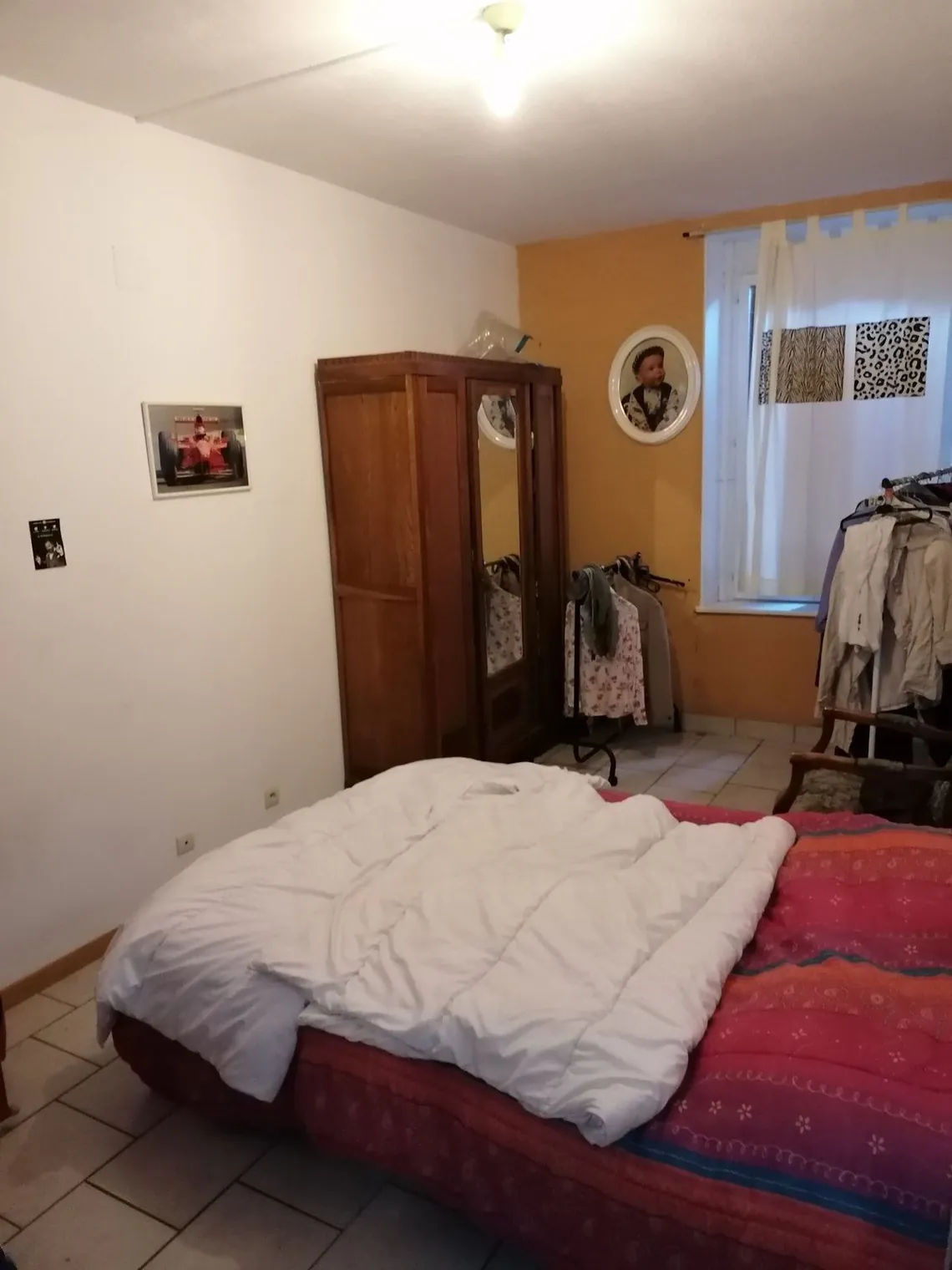 Chambre avec lit double, armoire ancienne et parquet.