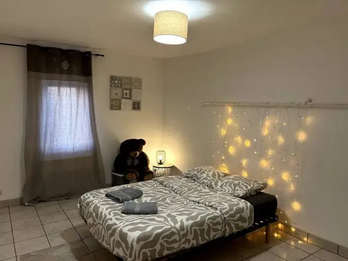 Chambre avec lit double, guirlande lumineuse et rideaux.