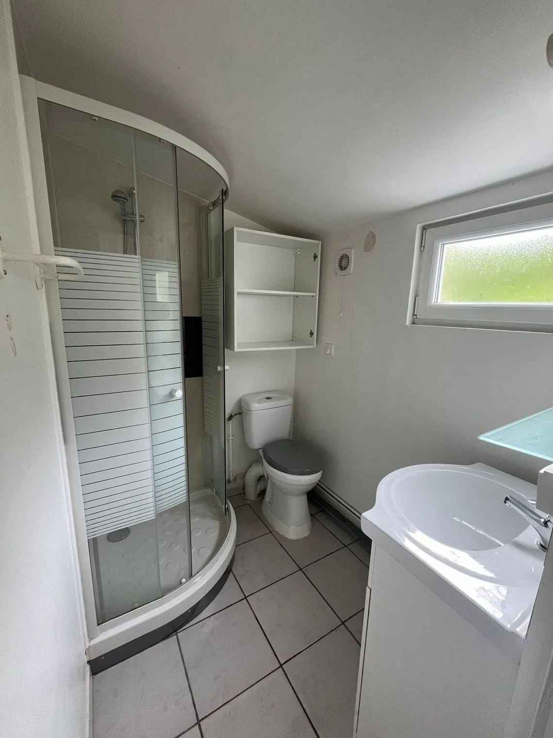 Salle d'eau avec cabine de douche d'angle, lavabo et WC.