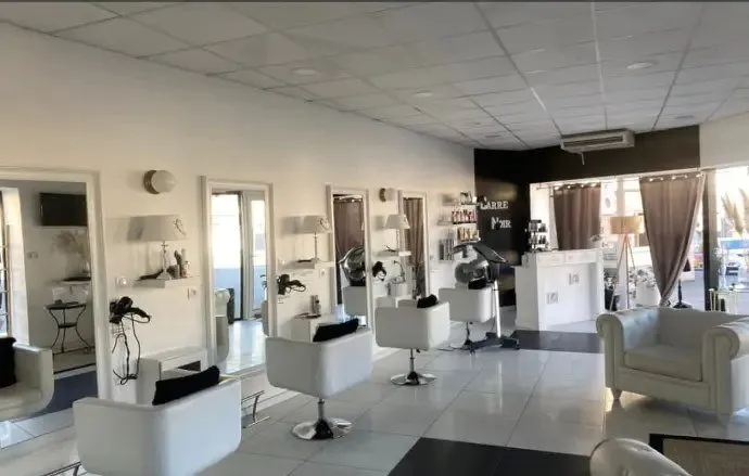 Salon de coiffure avec bacs, fauteuils et miroirs le long des murs.